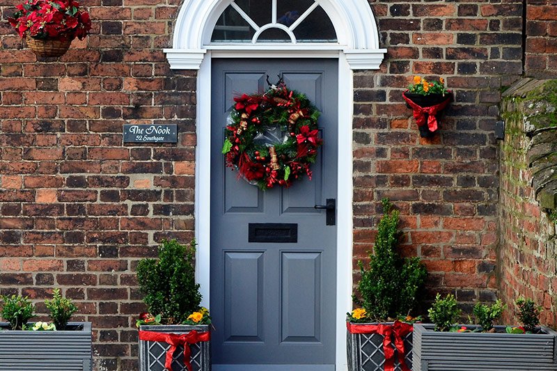 Christmas door decoration with wide ribbons for a beautiful home’s entrance