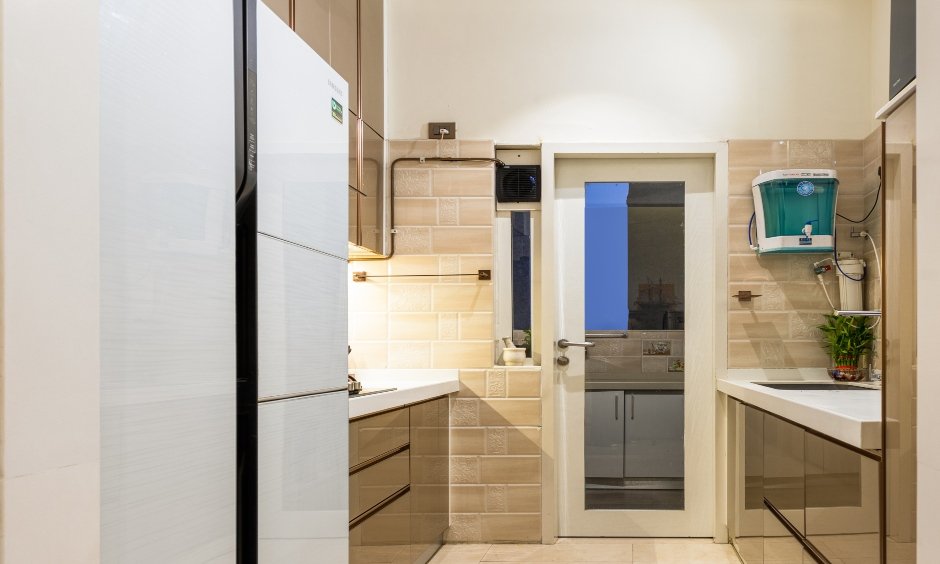 2 bhk apartment in Mumbai features a parallel kitchen with beige glossy finish and handleless cabinets