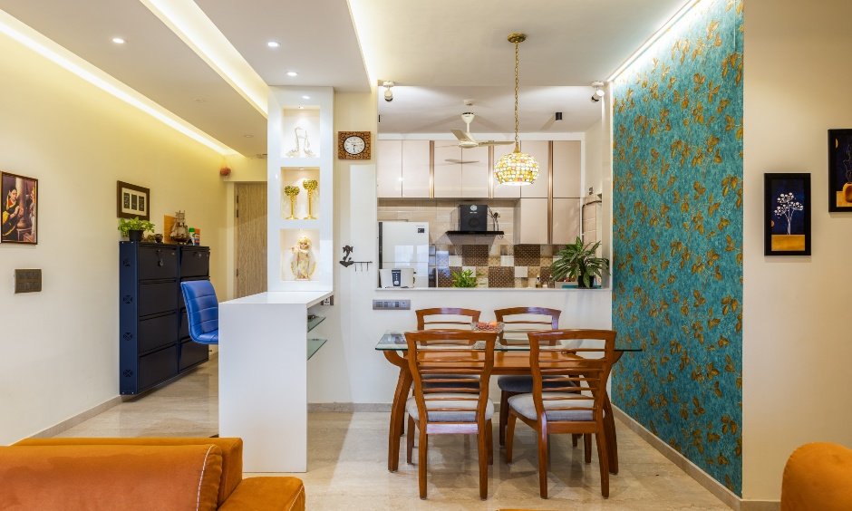 A wooden table and ladderback chairs furnish the Mumbai 2 bhk house's small dining room for a family of four